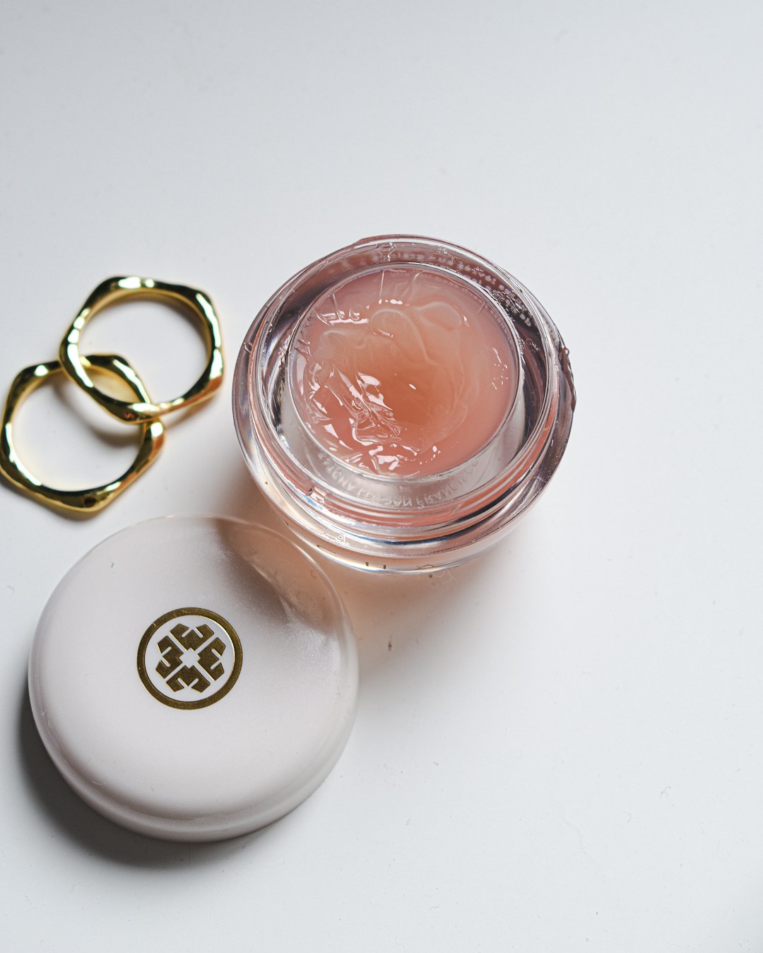 Close up shot of pot of Tatcha Lip Balm and jewellery by Makeup Brands a close-up of some jewelry