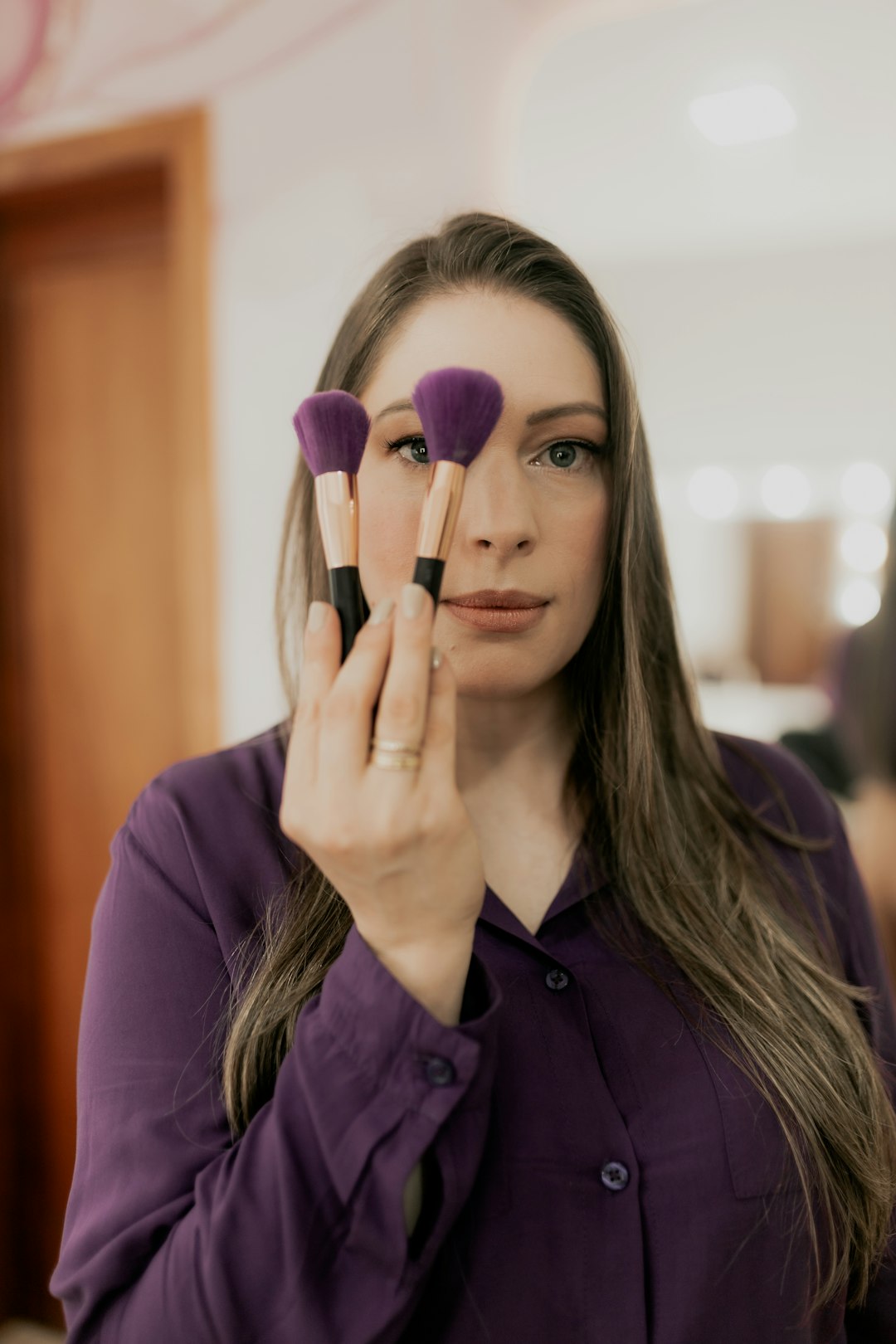 FAQ 🤔 by Makeup Brands A woman holding three makeup brushes in front of her face